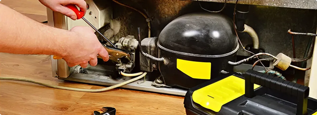 Refrigerator repair technician fixing the compressor and wiring in North Fort Myers, FL